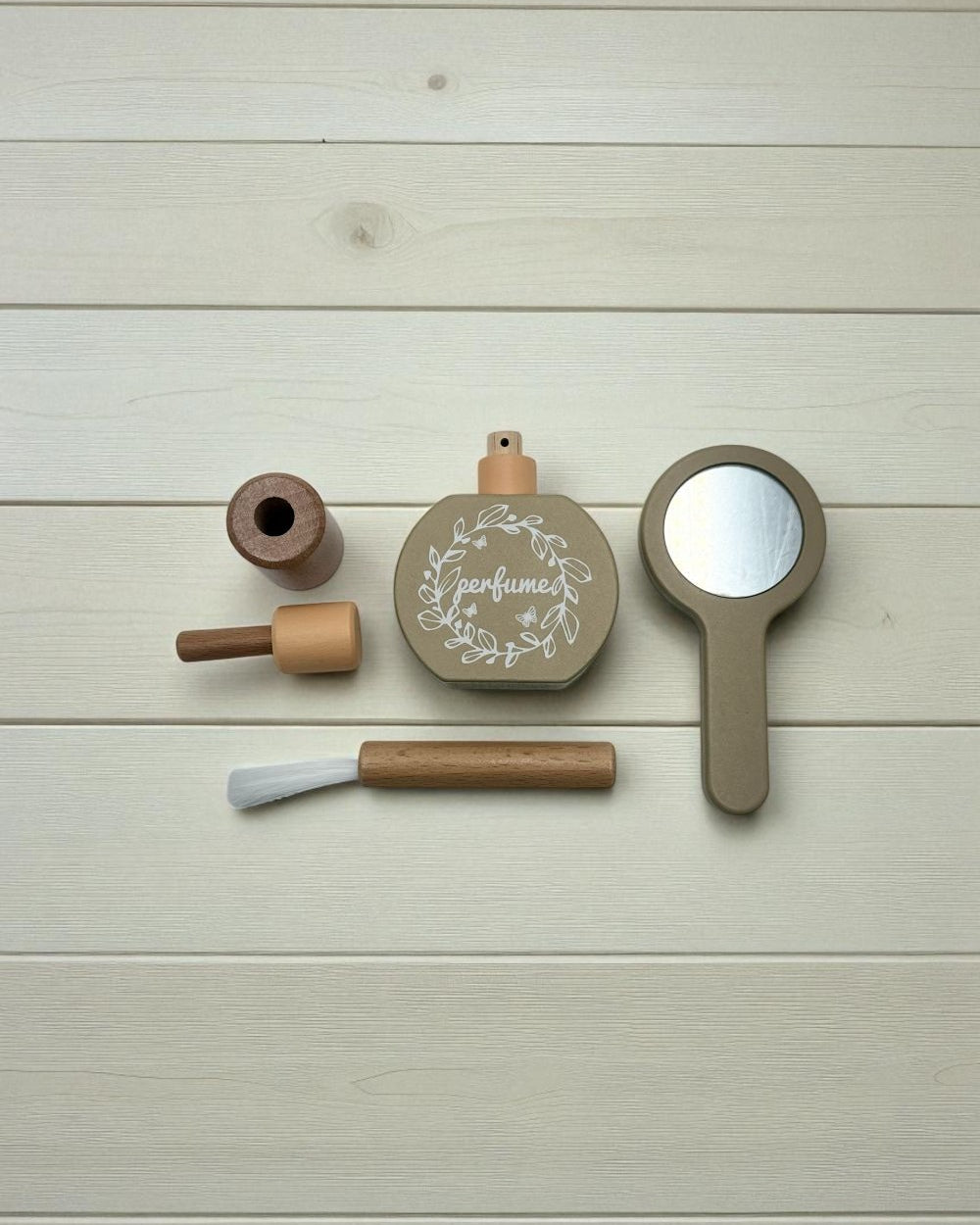 Set of wooden beauty products including a perfume bottle, brush, and mirror on a light wooden surface.