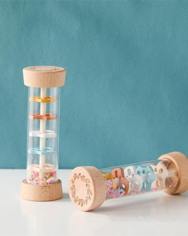 Wooden Montessori rain sound cylinder with natural beechwood ends and transparent center showing colorful discs