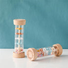 Wooden Montessori rain sound cylinder with natural beechwood ends and transparent center showing colorful discs