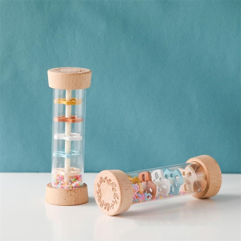 Wooden Montessori rain sound cylinder with natural beechwood ends and transparent center showing colorful discs