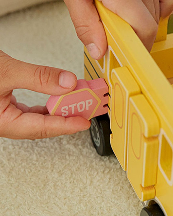 Child's hand placing wooden character figure on carpet showing figures sized for small hands