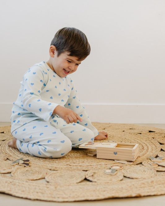 Child playing with a wooden toy on a round jute rug in a minimalistic room.