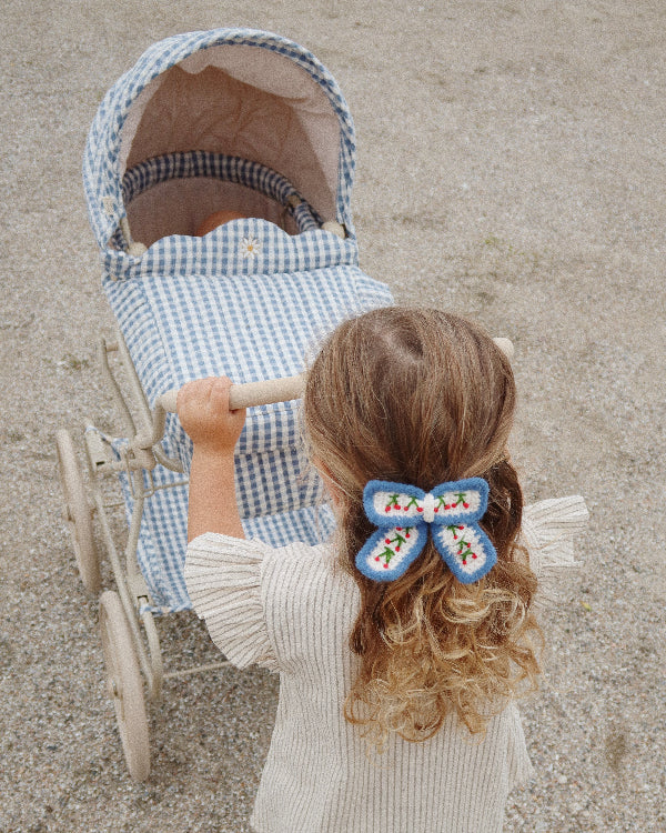 Classic navy and white gingham doll pram with four spoked wheels and sophisticated quilted fabric details
