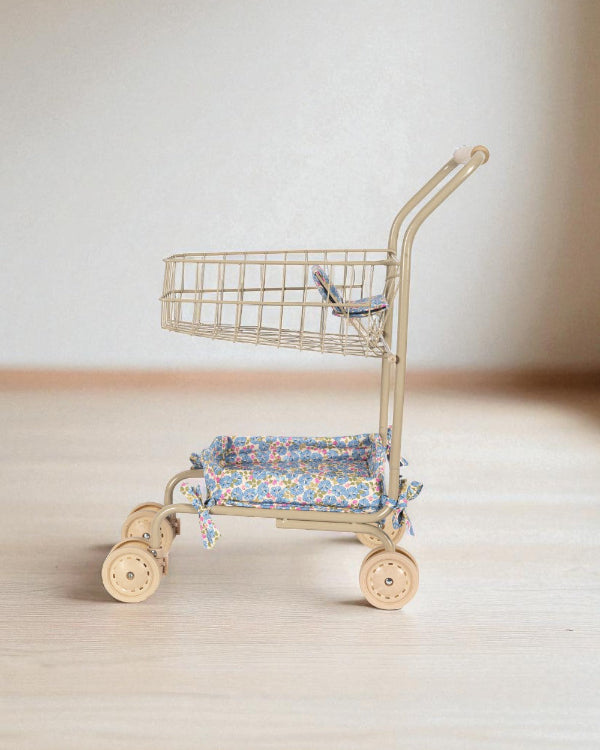 Side profile of premium toy shopping cart showing two-tier design with upper wire basket and lower padded seat platform