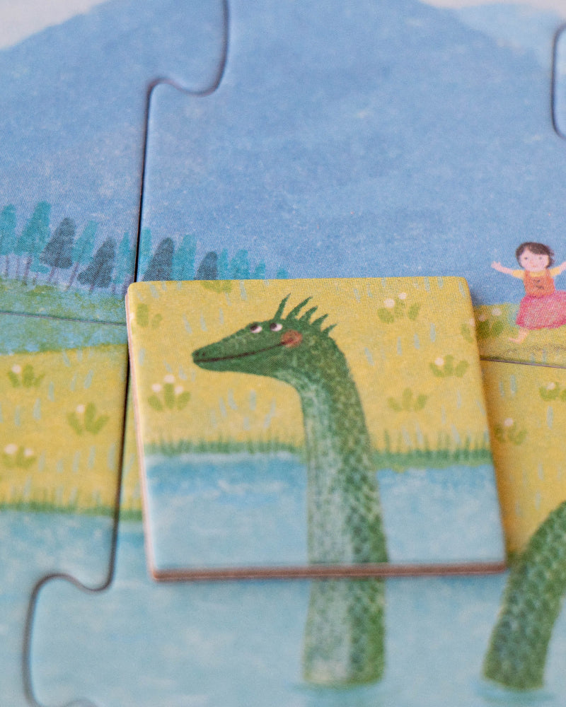 Children's puzzle with a dragon and a girl on a yellow platform, set against a scenic background.
