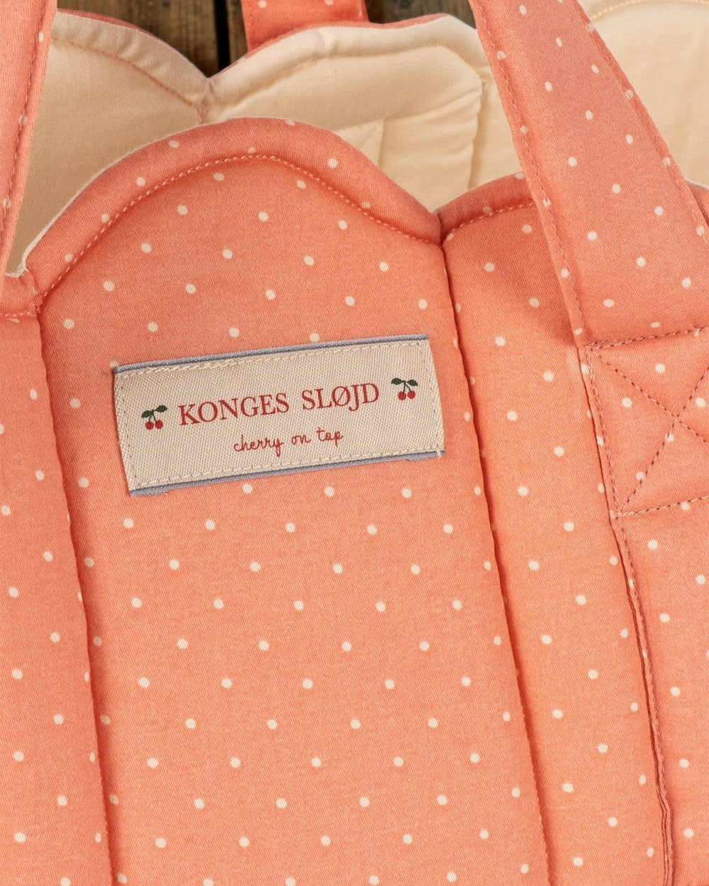 Playroom Collective Konges Sloejd quilted coral doll bassinet with white dots and scalloped cream lining detail