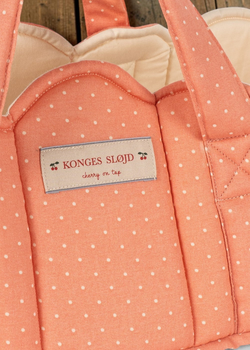 Playroom Collective Konges Sloejd quilted coral doll bassinet with white dots and scalloped cream lining detail