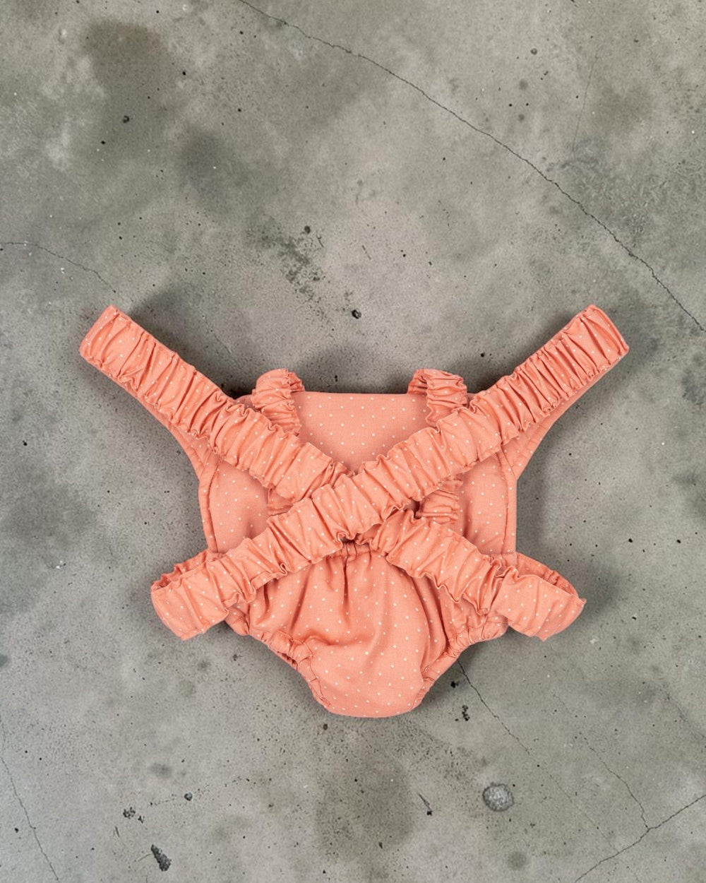 Playroom Collective Konges Sloejd doll carrier in rose coral cotton with white dots and flexible elastic straps.