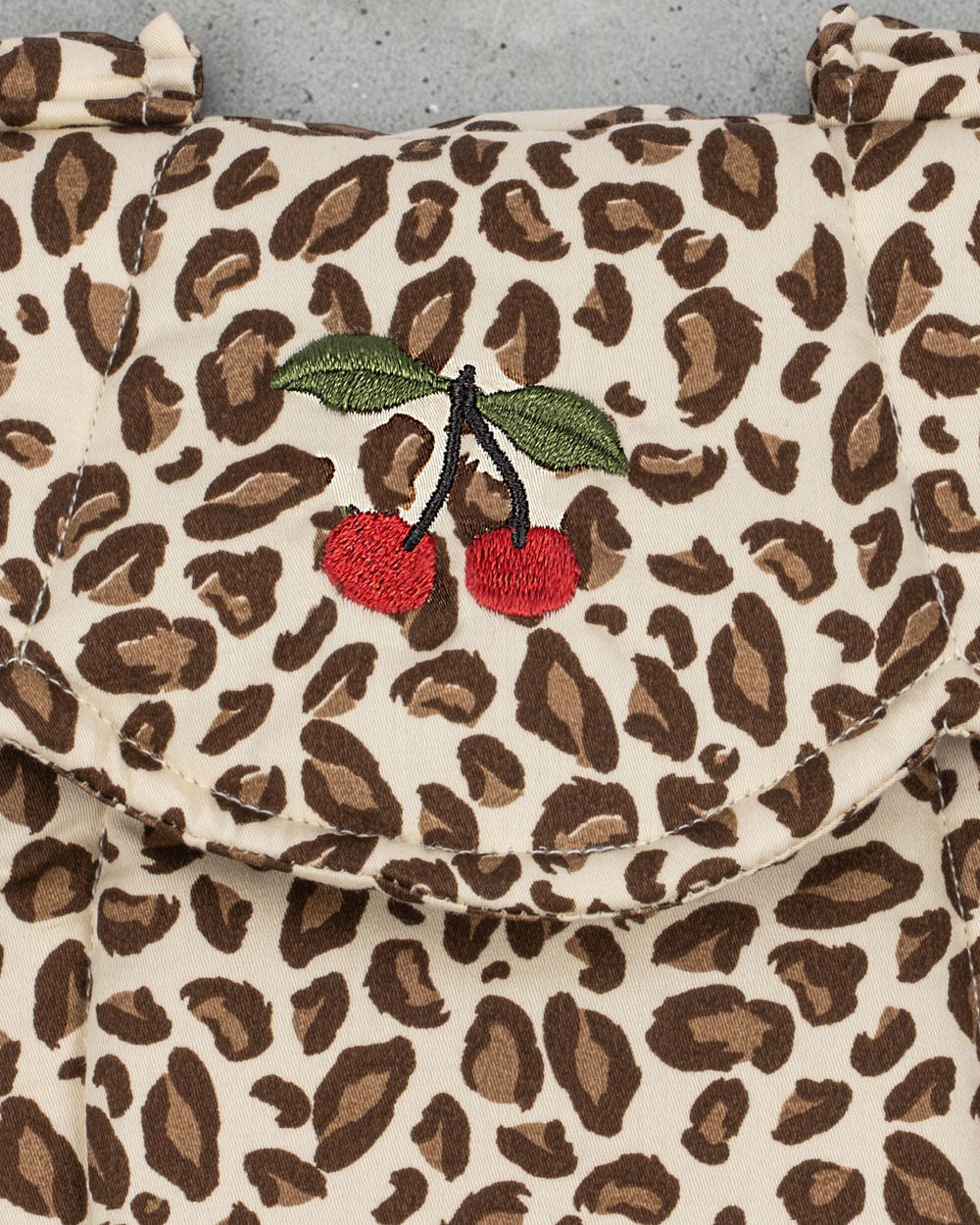 Playroom Collective Konges Sloejd baby doll carrier in cream and brown leopard print with embroidered cherry detail.
