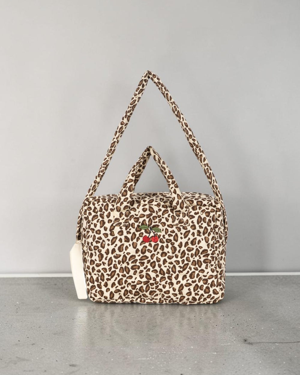 Playroom Collective Konges Sloejd leopard print cotton doll diaper bag with embroidered cherry detail and straps.