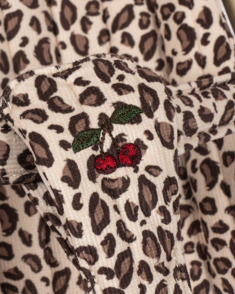 Playroom Collective Konges Sloejd doll stroller fabric featuring a cream and brown leopard print with cherry embroidery