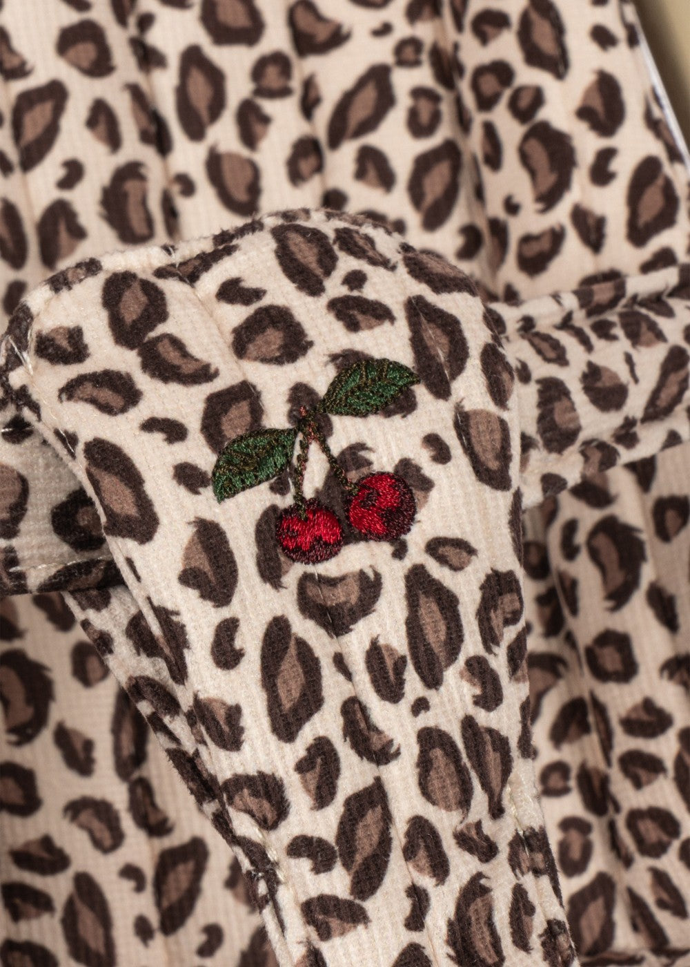 Playroom Collective Konges Sloejd doll stroller fabric featuring a cream and brown leopard print with cherry embroidery