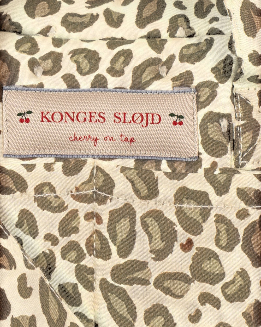 Playroom Collective Konges Sloejd doll diaper bag in cream and brown leopard print with cherry logo label