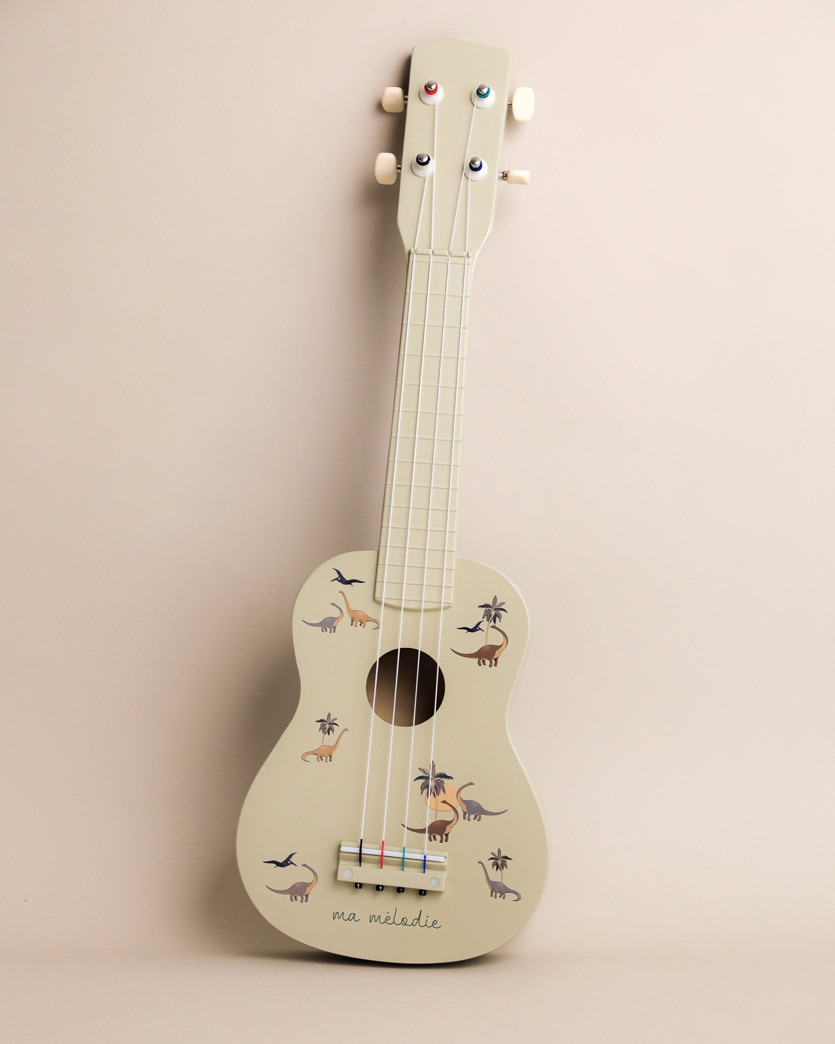 Dino print wooden ukulele with sage green finish and prehistoric creature designs scattered across body