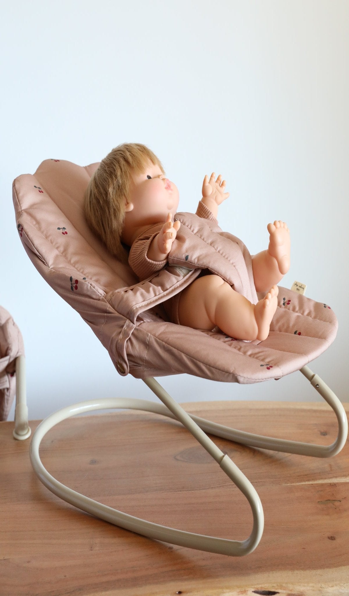 Miniature baby doll bouncer with realistic rocking motion for playroom fun