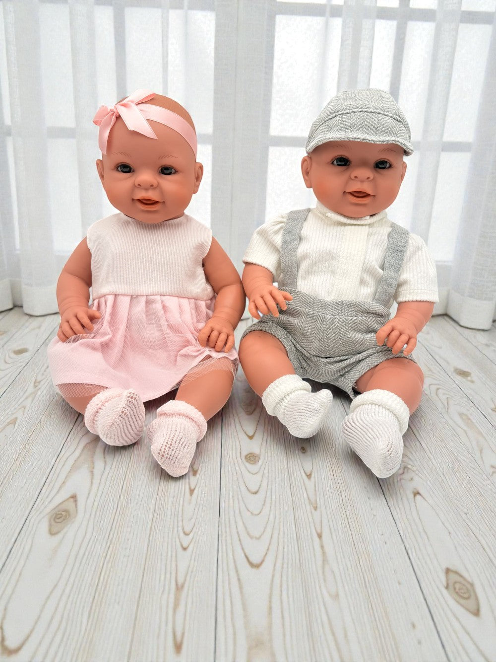 Spanish artisan-crafted baby dolls in grey herringbone and pink dress showing anatomically correct boy and girl options