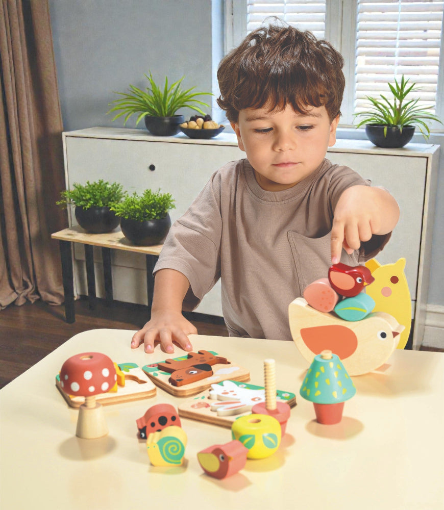 Child playing with wooden toys on a table in a room with plants and furniture.