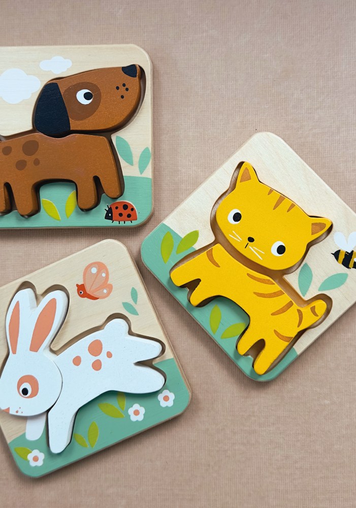 Three wooden animal puzzles of a dog, cat, and rabbit on a beige background.