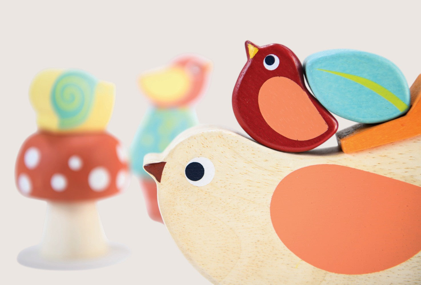 Colorful wooden toys including a bird, mushroom, and leaf on a light background