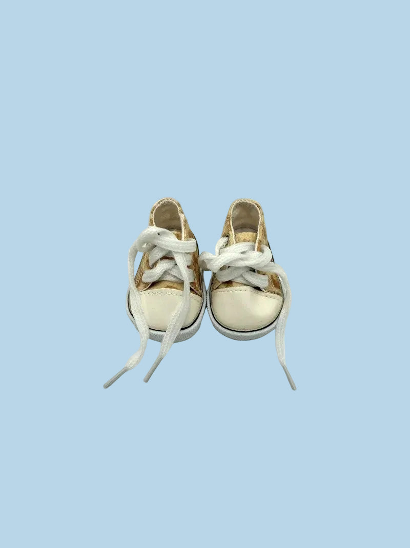 Pair of white sneakers with gold accents on a light blue background