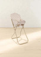 Cream-colored doll feeding chair showing coral and teal rose print with stable base design