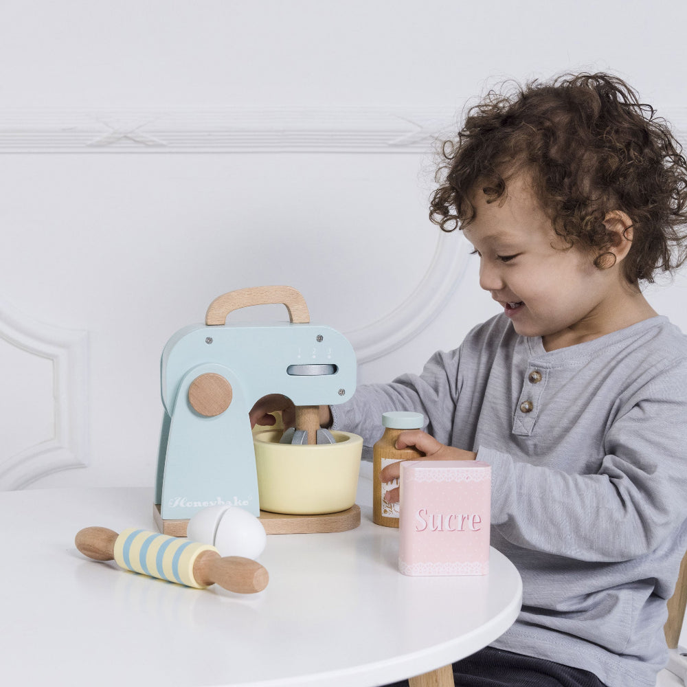 Child playing with a bakers kitchen set on a white table