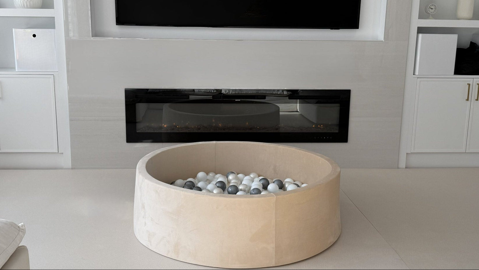 Modern living room with a round wooden fire pit table in front of a television.