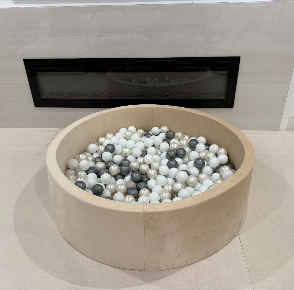 ball pit filled with multicolored balls in front of a modern fireplace.