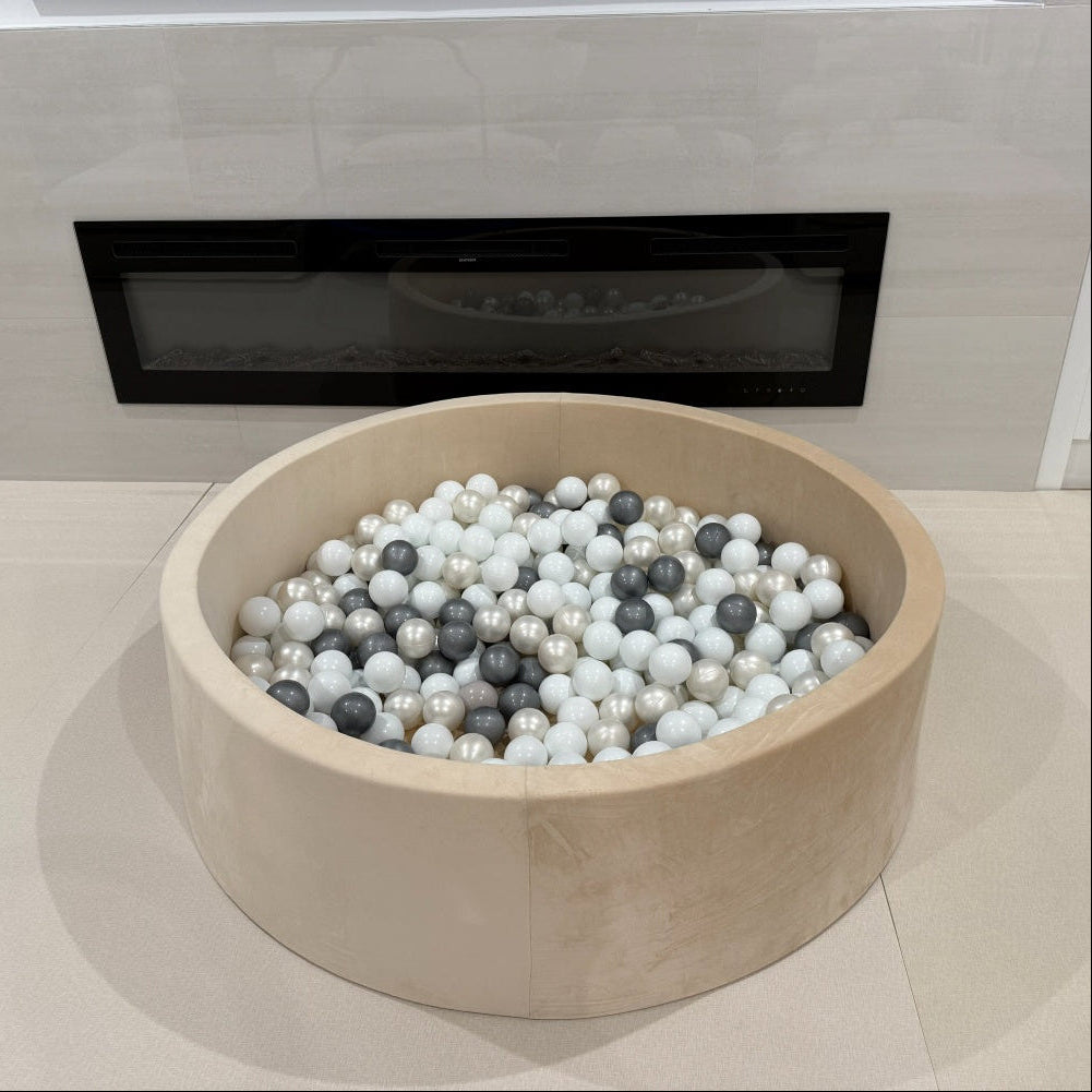ball pit filled with multicolored balls in front of a modern fireplace.