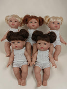Five dolls with styled hair in pigtails on a plain background