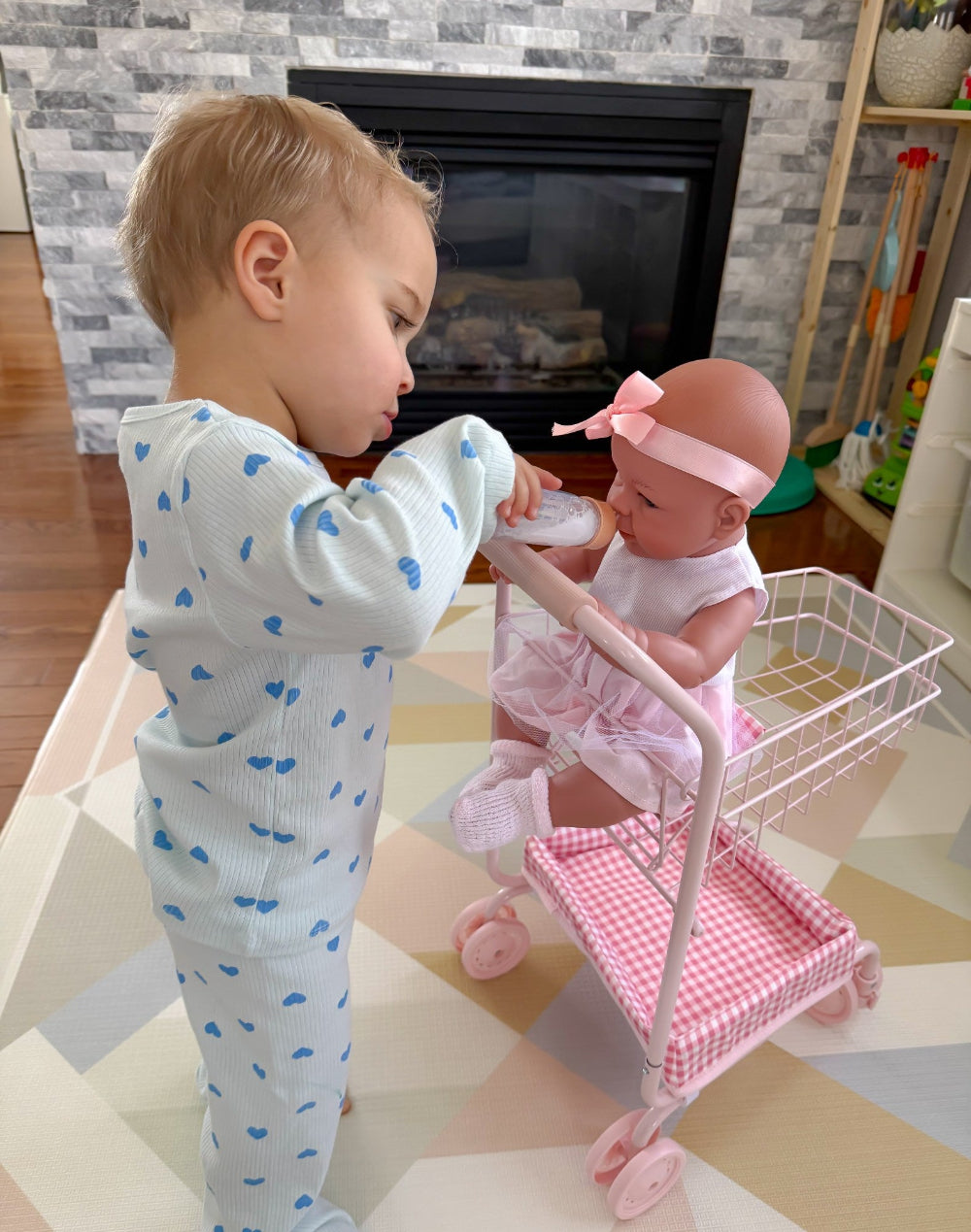 Child playing with a doll in a toy cart in a home setting