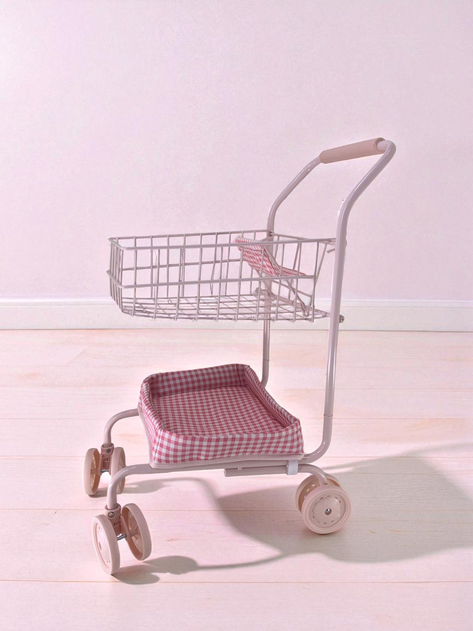 Side view of pink gingham doll cart showing two-tier design with upper basket and padded lower seat platform