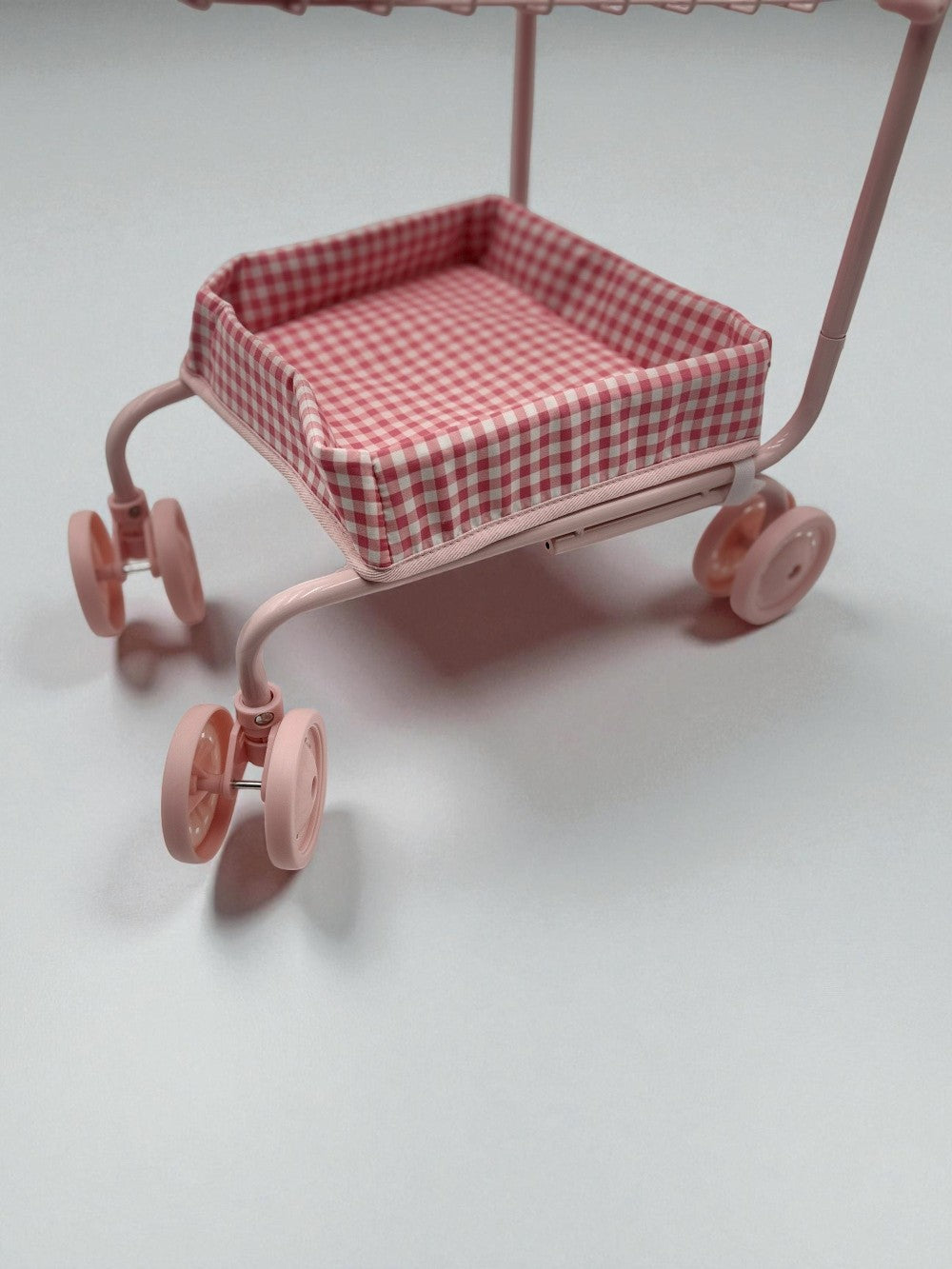 Pink toy cart with a checkered seat on a light gray background