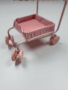 Pink toy cart with a checkered seat on a light gray background