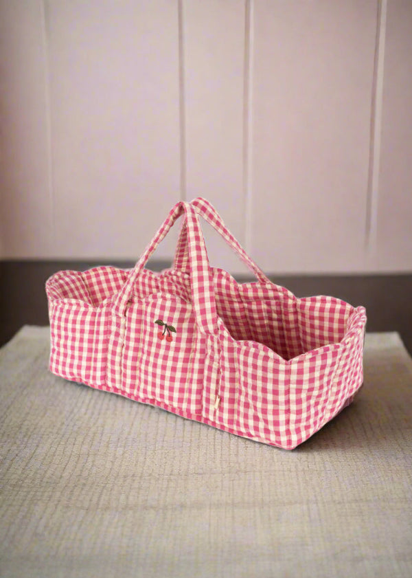 Pink gingham doll bassinet with classic checkered pattern and sturdy carrying handles