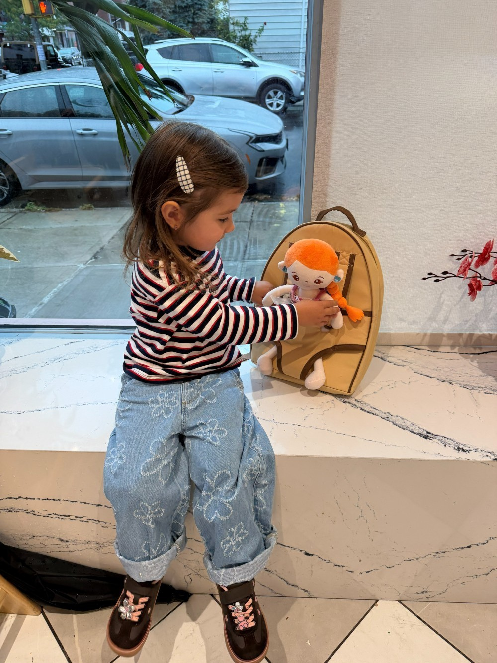 Child tucking in doll in the little carrier