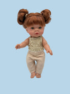 A doll with brown hair in two buns, wearing a beige patterned sleeveless top and matching ribbed pants, photographed against a plain light gray background.