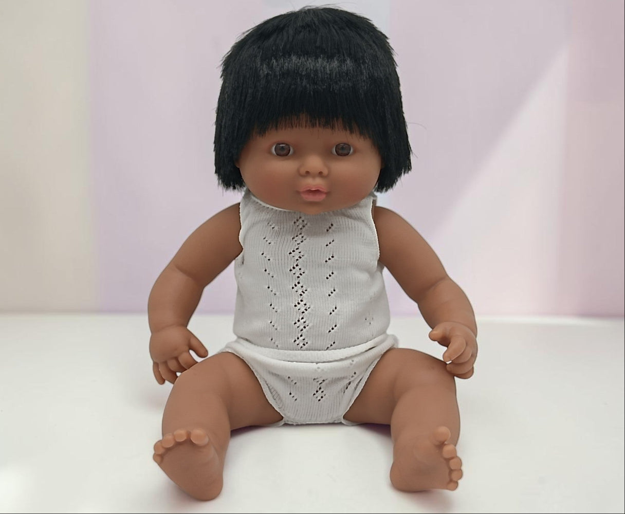 Doll with black hair wearing a white lace outfit on a white background