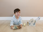 Child playing with a wooden toy on a wooden floor