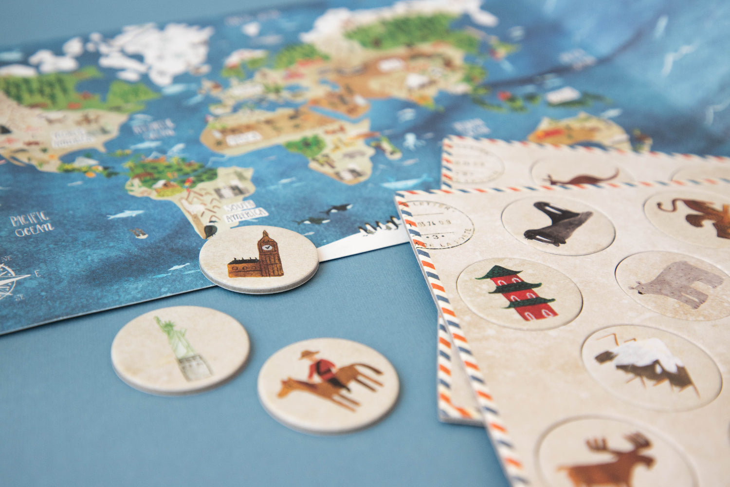 World map with travel-themed coasters and a notebook on a blue surface