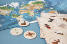 World map with travel-themed coasters and a notebook on a blue surface