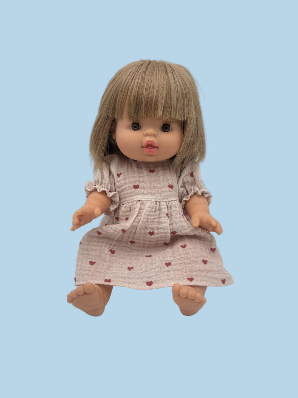 Doll wearing soft cotton muslin dress in mauve heart pattern matching Leni & Romi collection