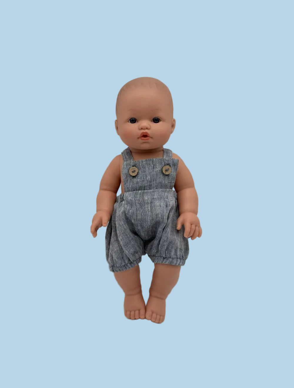 Bebenita doll wearing handmade chambray muslin overall with functional buttons, standing against white background