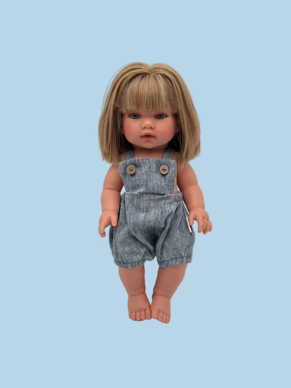 Doll wearing a denim overalls with a plain background