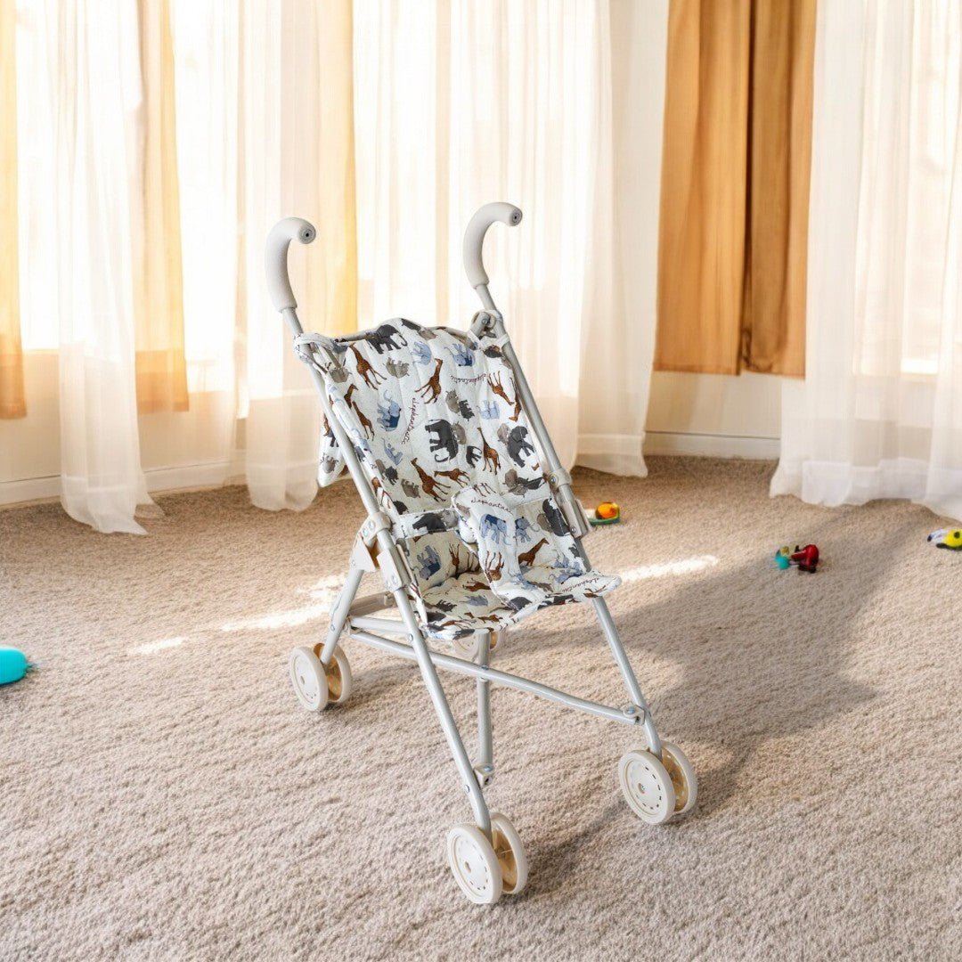 A white baby doll stroller with a pattern featuring elephants and other safari animals in browns and blues, displayed in a room setting.