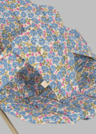 Close-up of Fleur Rosier print fabric showing cornflower blue flowers with pink accents and green leaves on cream background