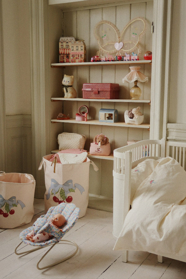 Child gently placing doll in floral bouncer during nurturing pretend play, developing empathy and care skills