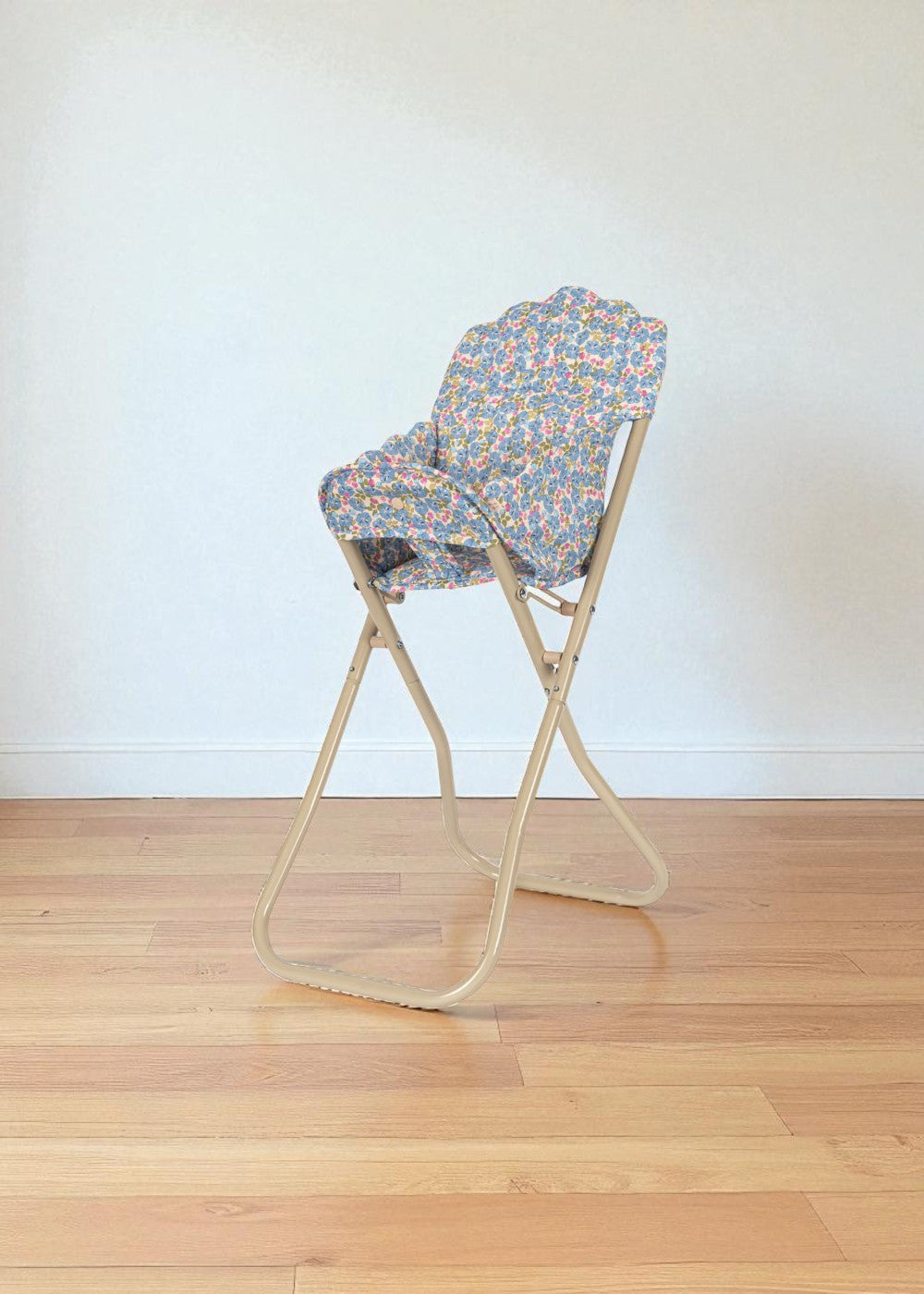 Side view of Fleur Rosier high chair showing foldable champagne metal frame in collapsed position for storage