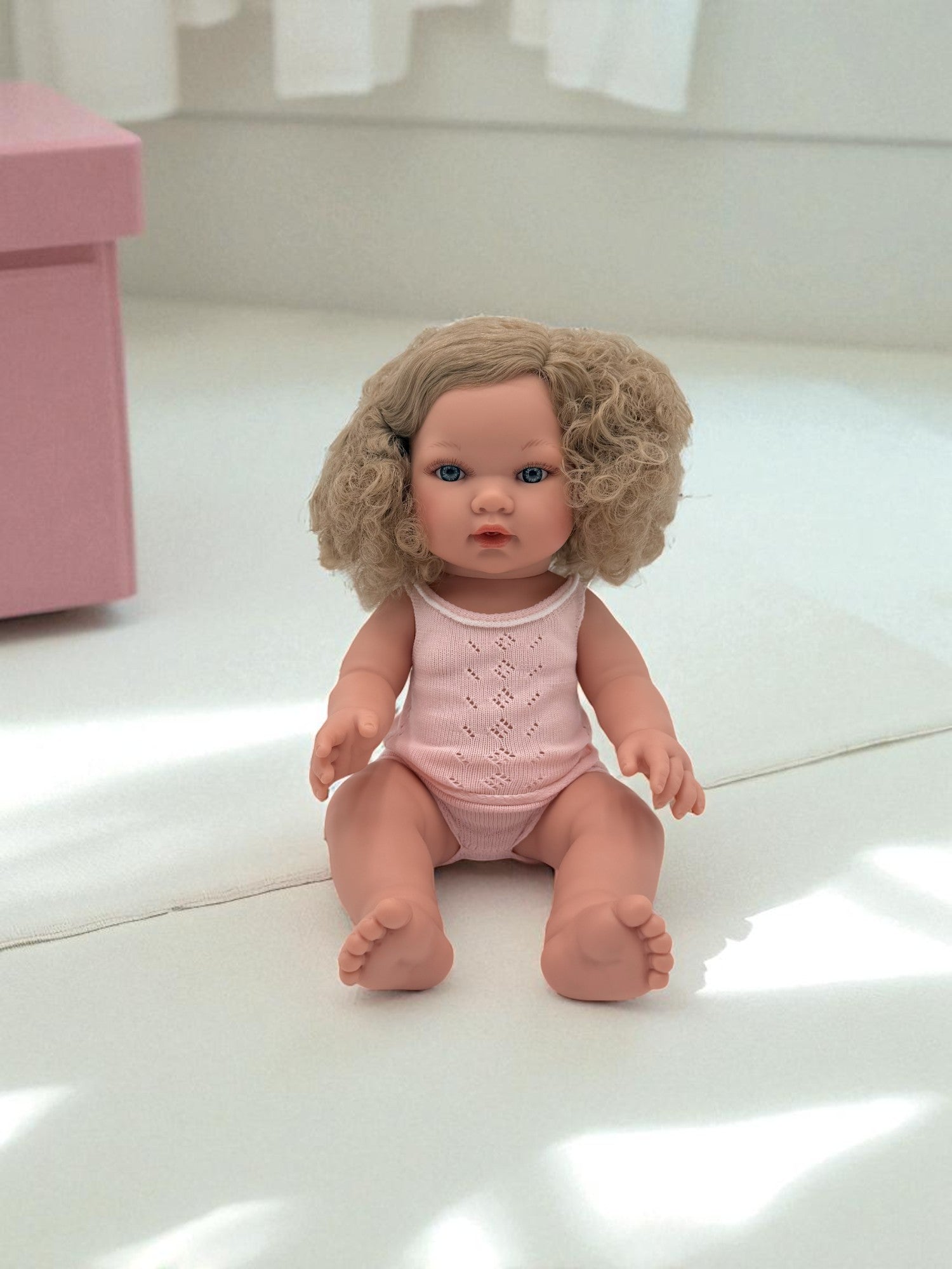 Blue-eyed realistic baby doll with curly blonde hair for sensory playroom activities