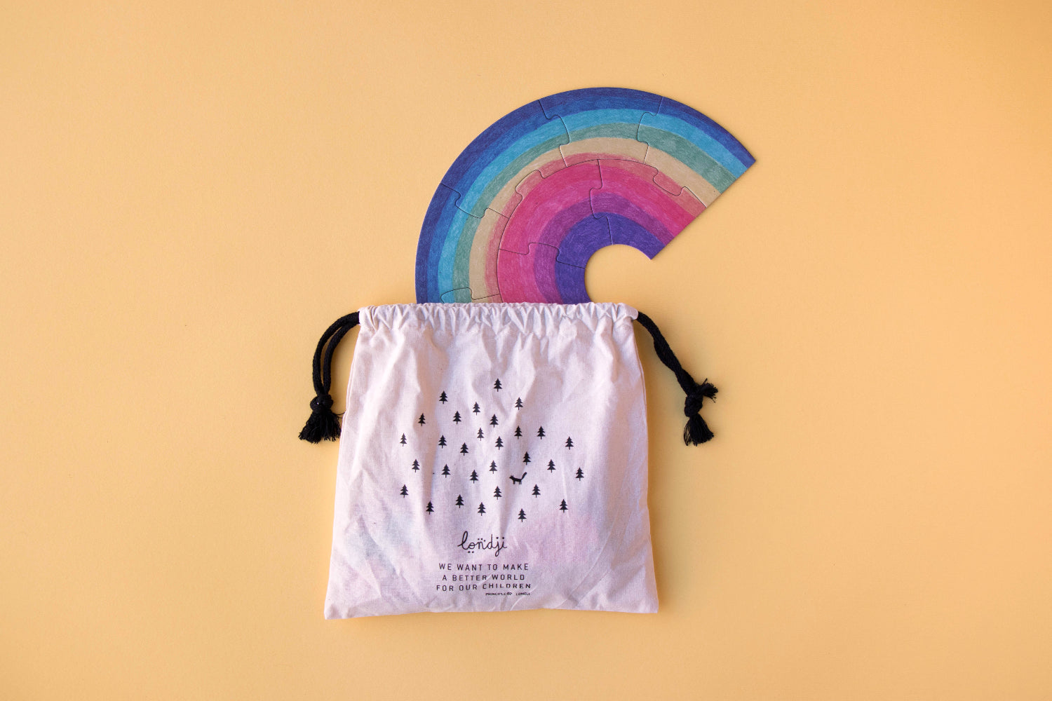 Colorful rainbow-shaped object on a white drawstring bag with text against a beige background